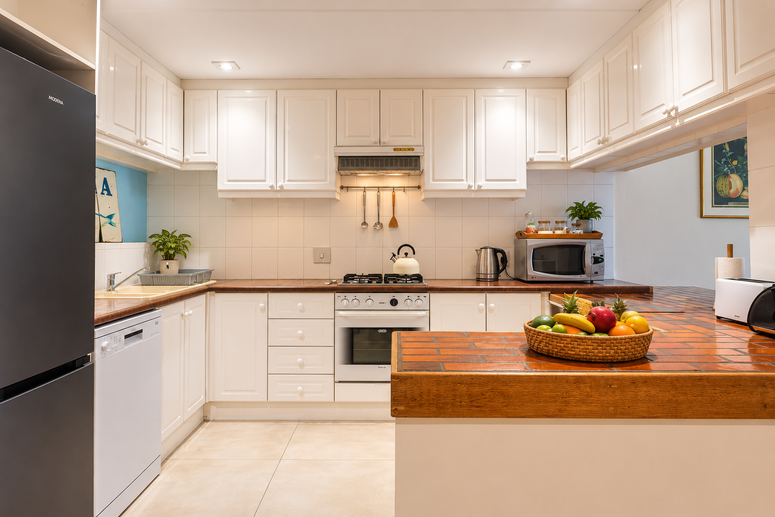 Fish Eagle Chalet kitchen with white cabinets, terracotta-tiled counters and a wooden breakfast bar holding a bowl of fruit