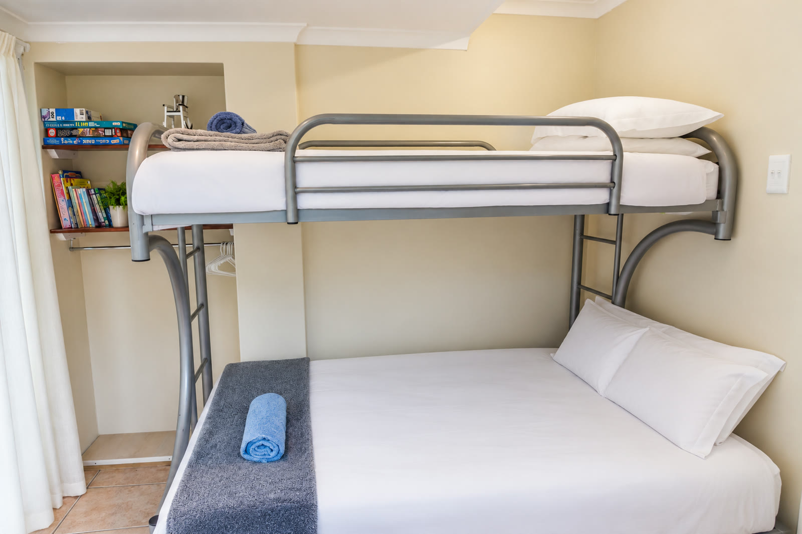 Children's bunk room at Loerie Chalet with twin-over-double bunk beds in white linen and a shelf of games and books