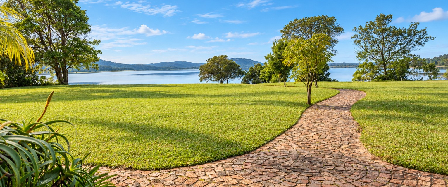 The lawns and stone walkway in front of the chalets, looking across Swartvlei Lake to the hills beyond