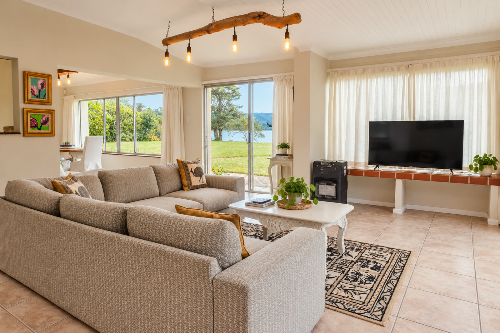 Loerie lounge with sofas, a coffee table, television and sliding doors overlooking the lake