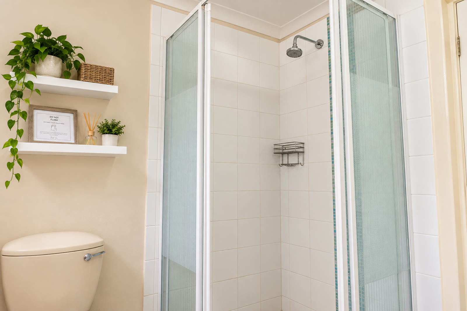 Loerie Chalet bathroom with a reeded-glass shower, floating shelves with trailing plants and an almond toilet