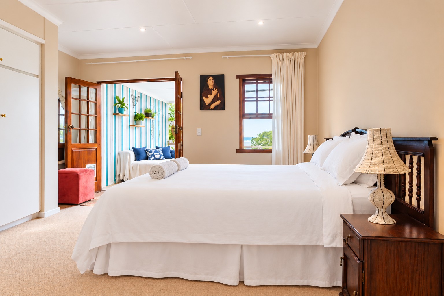 Sunbird Chalet bedroom with crisp white linen, a window over the treetops and doors opening to the sunroom